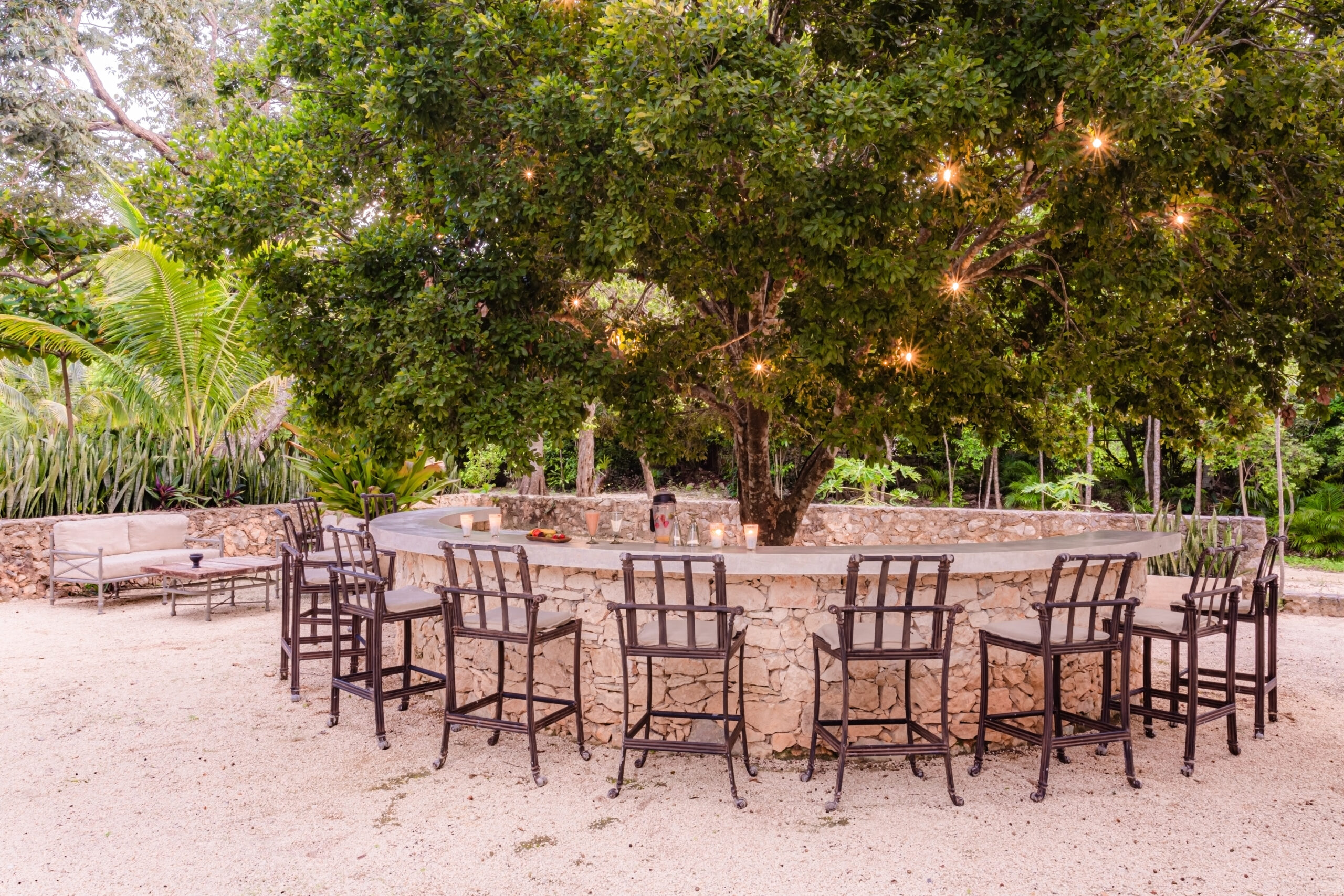 Long dinner table lit under a tree at an outdoor property